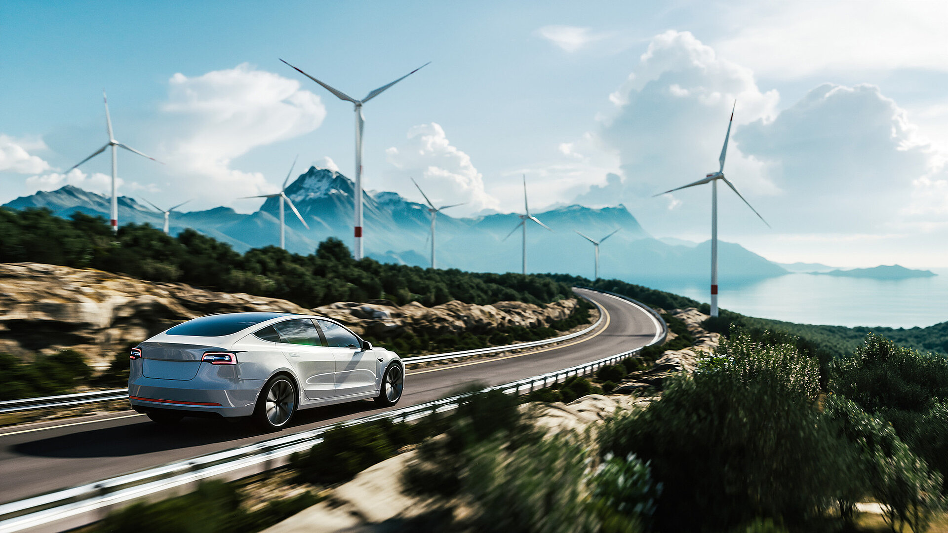 Ein Elektroauto fährt über eine bergige Landstraße mit Windkraftanlagen im Hintergrund.