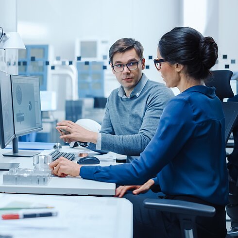 A woman and a man are working on the computer.